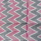 A close-up of an antique woven textile with a repeating chevron pattern in pink, black, and white, featuring a partial pink border along the bottom edge.