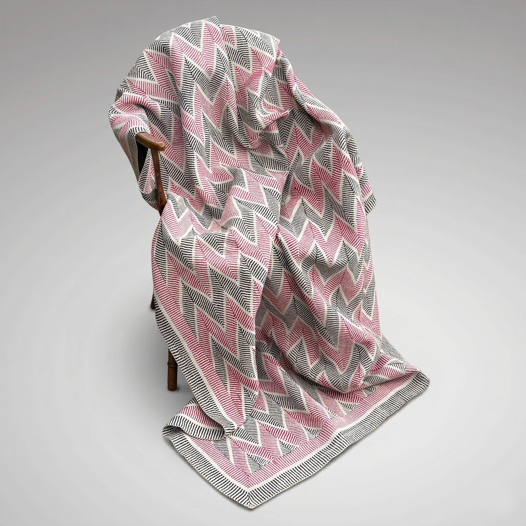 Main picture - An antique Kantha throw blanket with a pink, gray, and white chevron pattern draped over a wooden chair against a neutral grey background.