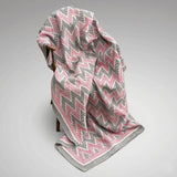Main picture - An antique Kantha throw blanket with a pink, gray, and white chevron pattern draped over a wooden chair against a neutral grey background.